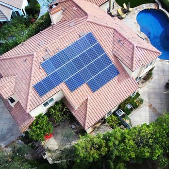 Solar panels on a Spanish tile roof beside a pool